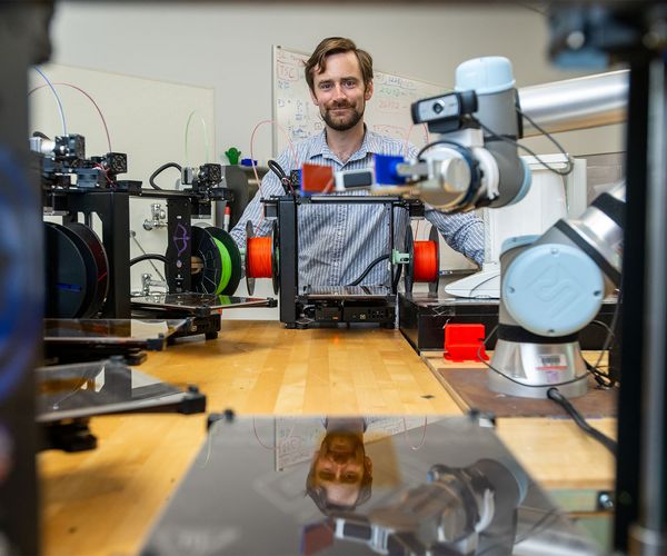 Keith Brown in his Boston University lab with 3D printers and a robotic arm